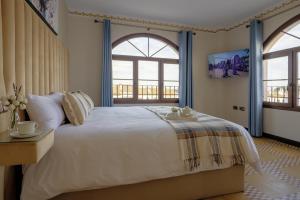 a bedroom with a large bed and two windows at Palacio de la Canaliega in El Rocío