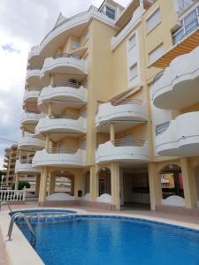 an apartment building with a swimming pool in front of it at Bitacora I Solo Familias Serviplaya!!! in Playa de Xeraco