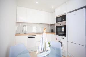 una cucina con mobili bianchi, tavolo e sedie di Barreiro Charming House a Barreiro