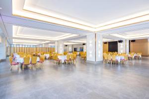 a banquet hall with white tables and yellow chairs at Zhuhai New Aolin Apartment - Tangjiawan Station in Zhuhai