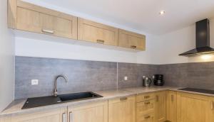 une cuisine avec des armoires en bois et un évier dans l'établissement Gites des falaises de Longues 6personnes, à Longues-sur-Mer