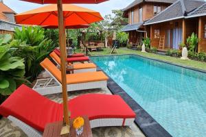 a pool with chairs and umbrellas next to a house at Villa Felise Sanur in Sanur