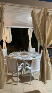 a white table with white chairs and a white curtain at Casa Isabell Con Piscina Privata in San Teodoro