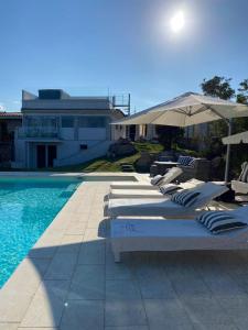 a row of lounge chairs and an umbrella next to a pool at Casa Isabell Con Piscina Privata in San Teodoro