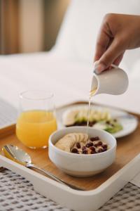 uma pessoa a deitar molho numa tigela de comida num tabuleiro em NERIUM Hotel em Ksamil