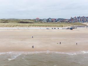 a group of people walking on the beach at Apartment De Zeeparel by Interhome in Egmond aan Zee
