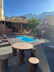 a patio with a table and stools and a pool at Suítes Grãos do Alto Caparaó in Caparaó Velho