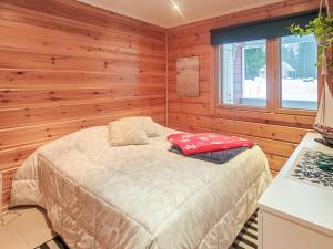 ein Schlafzimmer mit einem Bett in einer Holzhütte in der Unterkunft Holiday Home Tinttityy by Interhome in Tahkovuori