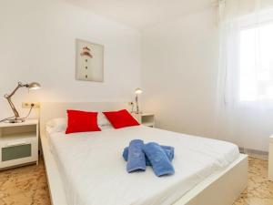 una camera da letto con un letto bianco con cuscini rossi di Apartment Garbinada by Interhome a Tossa de Mar