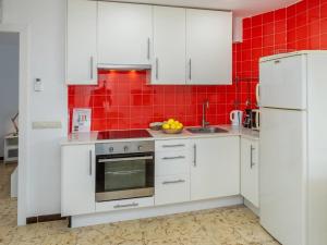 una cucina con armadi bianchi e una parete di piastrelle rosse di Apartment Garbinada by Interhome a Tossa de Mar