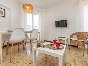 un soggiorno con tavolo, sedie e televisione di Apartment Garbinada by Interhome a Tossa de Mar