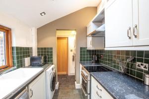 une cuisine avec des placards blancs et du carrelage vert dans l'établissement Central Two Bed Cottage On Watergate Street by Cheshire Escapes, à Chester