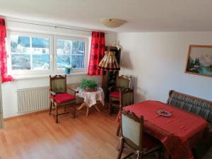 a dining room with a table and chairs and red curtains at Ferienwohnung Allgäuflair in Rieden am Forggensee