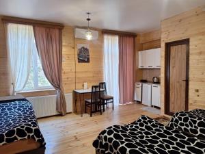 a room with two beds and a table and a kitchen at Hotel okriba in Tqibuli