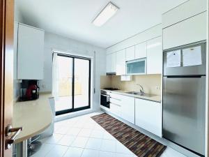 a kitchen with white cabinets and a stainless steel refrigerator at ApuliaMar Apartment in Apúlia