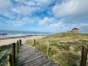 a wooden path to a beach with a building on a hill at ApuliaMar Apartment in Apúlia