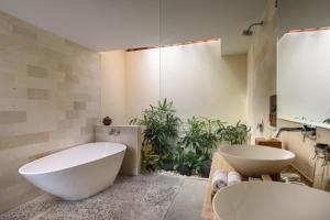 a bathroom with a large white tub and a sink at Anandathu Villas in Canggu