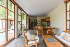 a living room with a table and chairs and windows at Anandathu Villas in Canggu +10 photos