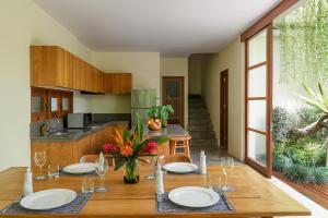 a dining room with a table with plates and wine glasses at Anandathu Villas in Canggu
