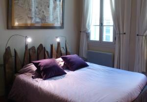 a bedroom with a bed with purple pillows and a window at Les Remparts in Avignon