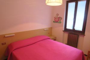 une chambre avec un lit avec une couverture rose dans l'établissement Appartamento Aurora, à Molina di Ledro