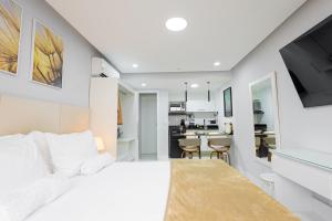 Un dormitorio con una cama blanca y una cocina. en Studio Praia do jardim 1 205A, en Angra dos Reis