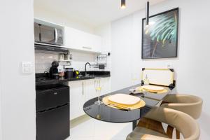 una cocina con electrodomésticos en blanco y negro y una mesa en Studio Praia do jardim 1 205A, en Angra dos Reis