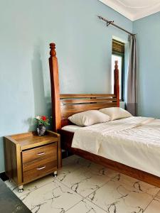 a bedroom with a bed with a wooden frame and a night stand at Kisubi Forest View in Entebbe