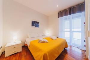 a bedroom with a yellow bed with towels on it at Wow Waterfront Apartment in Bari