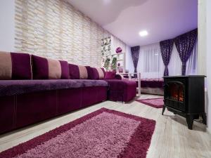 a living room with a purple couch and a stove at Purple Suite in Sinaia
