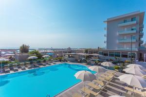 a view of a pool with chairs and umbrellas at Hotel Caesar in Lido di Savio