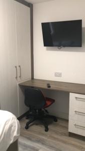 a bedroom with a desk with a television and a chair at Lancaster Apartment in Leicester