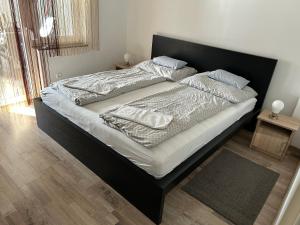 sypialnia z dużym łóżkiem z czarną ramą w obiekcie Komo Apartment w mieście Bük