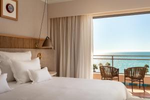 a bedroom with a large bed with a view of the ocean at Grande Real Santa Eulalia Resort & Hotel Spa in Albufeira