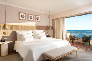 a bedroom with a large white bed and a balcony at Grande Real Santa Eulalia Resort & Hotel Spa in Albufeira