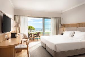 a hotel room with a large bed and a view of the ocean at Grande Real Santa Eulalia Resort & Hotel Spa in Albufeira