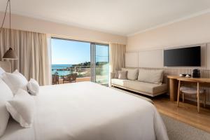 a hotel room with a large bed and a large window at Grande Real Santa Eulalia Resort & Hotel Spa in Albufeira