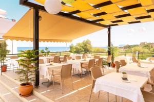 a restaurant with white tables and chairs and the ocean at Pegasus Hotel in Stalos