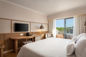 a hotel room with a bed and a desk and a television at Grande Real Santa Eulalia Resort & Hotel Spa in Albufeira