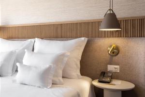 a bed with white pillows and a phone on a table at Grande Real Santa Eulalia Resort & Hotel Spa in Albufeira