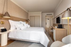 a bedroom with a large white bed and a desk at Grande Real Santa Eulalia Resort & Hotel Spa in Albufeira