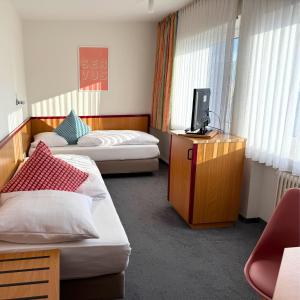 a hotel room with two beds and a television at Colourful Hotel in Bielefeld