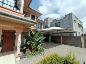 a house with a patio with an umbrella at 4Br Beautiful Mansion Mombasa rd in Nairobi