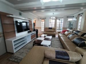 a living room with a couch and a flat screen tv at 4Br Beautiful Mansion Mombasa rd in Nairobi