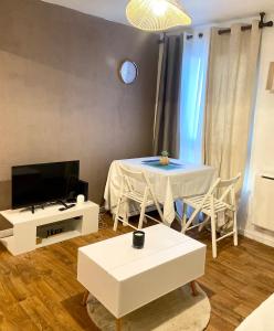 un salon avec une table et une télévision dans l'établissement Cozy studio, à Brétigny-sur-Orge