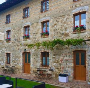 a stone building with tables and chairs in front of it at quiwolf in Cassacco