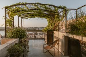 an archway with plants on a building with a chair at SCALA by Valletta Vintage in Valletta