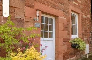 a brick building with a white door and a window at Ploughmans Cottage in Brampton