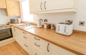 a kitchen with white cabinets and a wooden counter top at Ploughmans Cottage in Brampton +3 photos