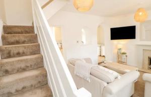 a white living room with a white couch and stairs at Ploughmans Cottage in Brampton
